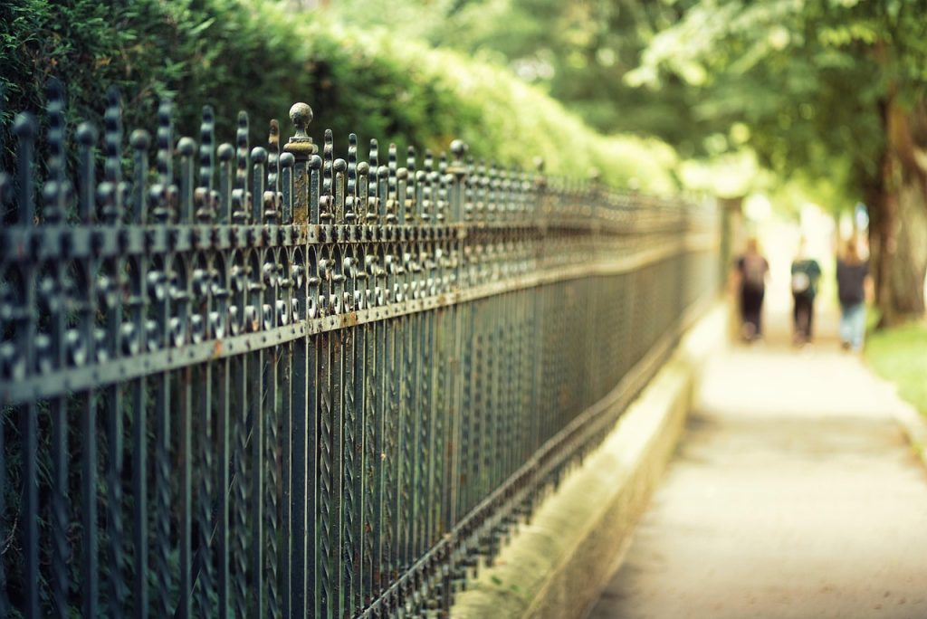 Long wrought iron fence Toronto with pedestrians walking by on sidewalk
