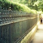 Long wrought iron fence Toronto with pedestrians walking by on sidewalk