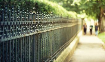 Long wrought iron fence Toronto with pedestrians walking by on sidewalk